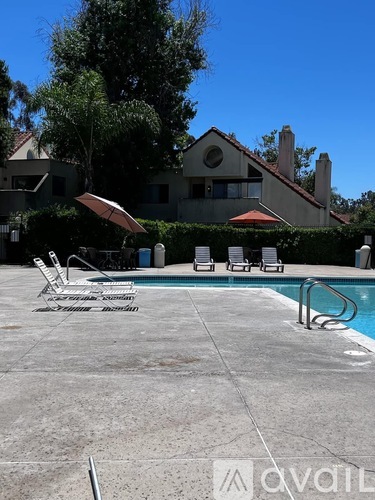 A pool with chairs and a house in the background.