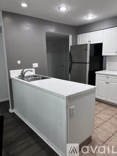 A kitchen with a black refrigerator and white cabinets.