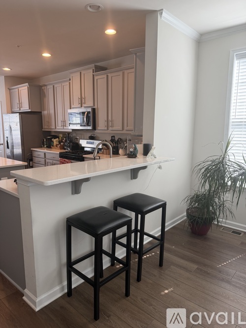 A kitchen with a white counter and black stools.