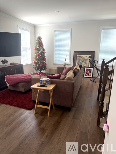 A living room with a Christmas tree and a flat screen TV.