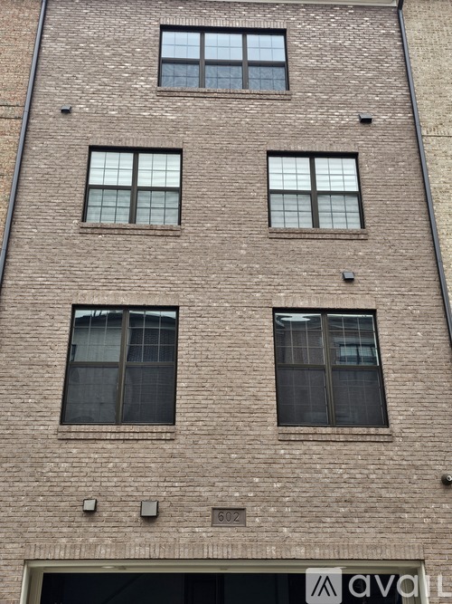 A tall brick building with three windows on the second floor.