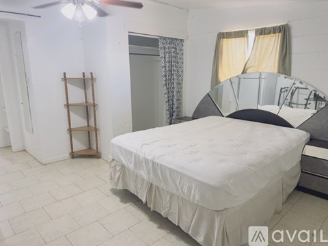 A bedroom with a white bed, a mirror, and a wooden ladder.