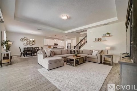 A spacious living room with a white sofa set and a wooden floor.