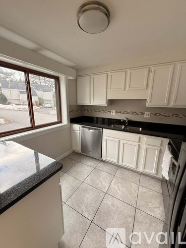 A kitchen with white cabinets and a black countertop.