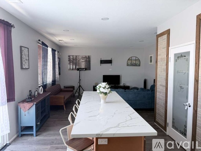 A dining room with a white table and chairs, a blue sofa, and a TV on the wall.