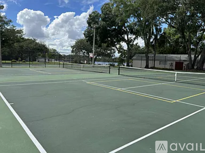 A tennis court with a net and trees in the background.