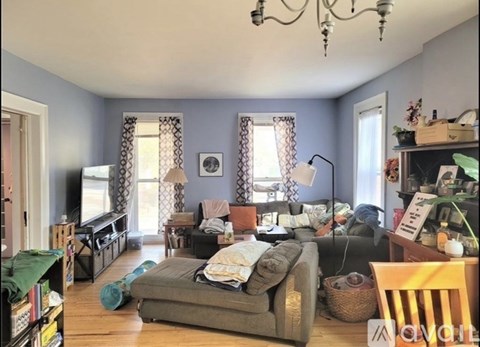 A living room with a grey couch and a chandelier.