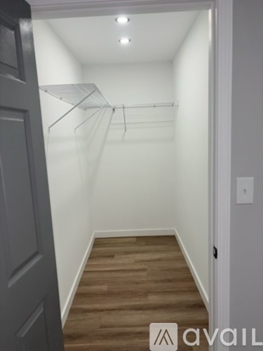 A hallway with a wooden floor and a white wall.