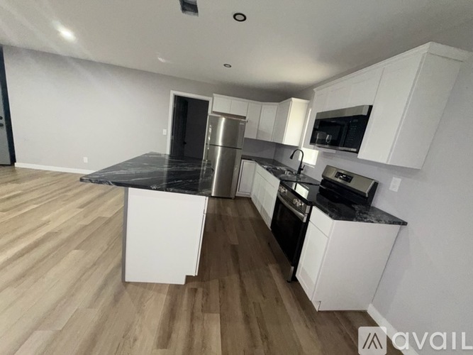 A kitchen with white cabinets and a black countertop.
