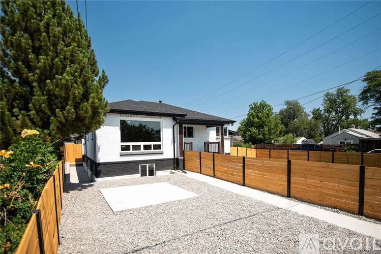A modern house with a white exterior and a gravel driveway.