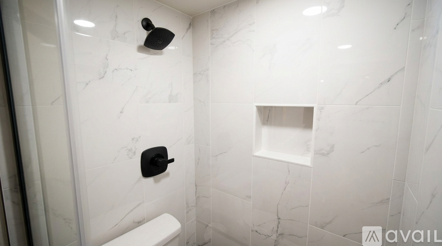A white toilet in a marble bathroom with a shelf above it.