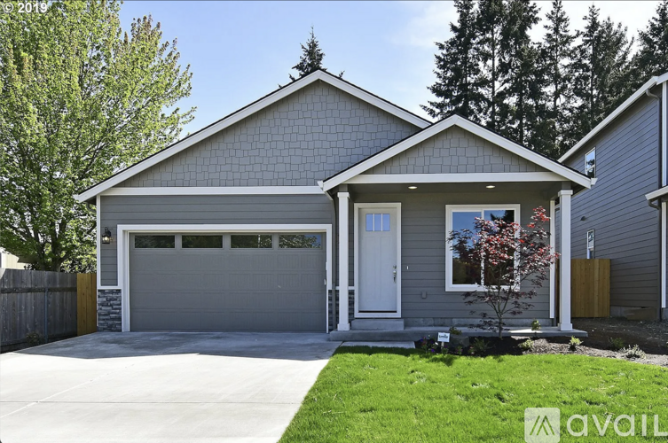 A house with a garage and a tree in front of it.