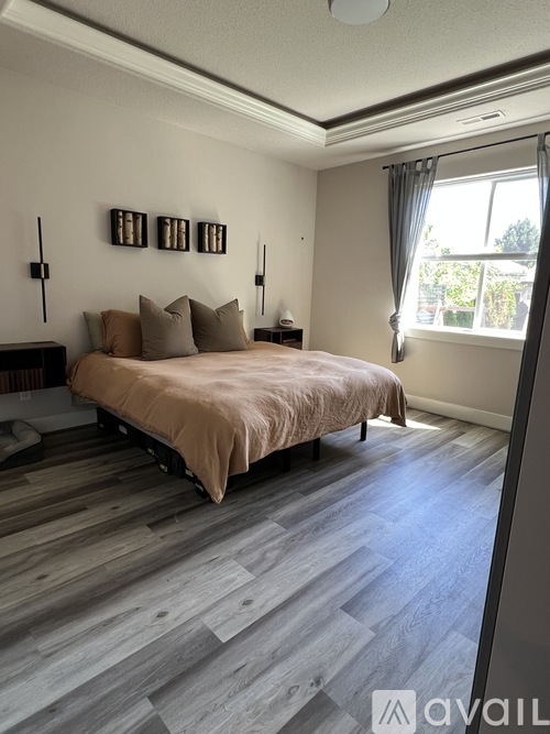 A bedroom with a bed, pillows, and a window.