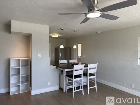A dining room with a table set for two and a ceiling fan.