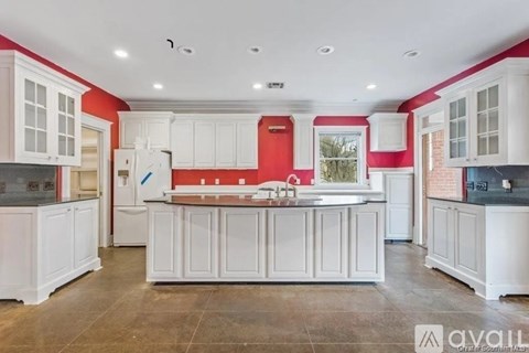 A kitchen with white cabinets and a red backsplash.