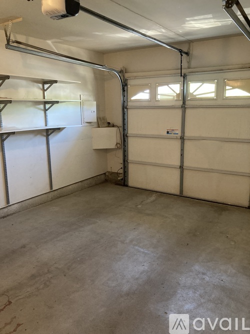 A spacious garage with a white door and shelves on the left side.
