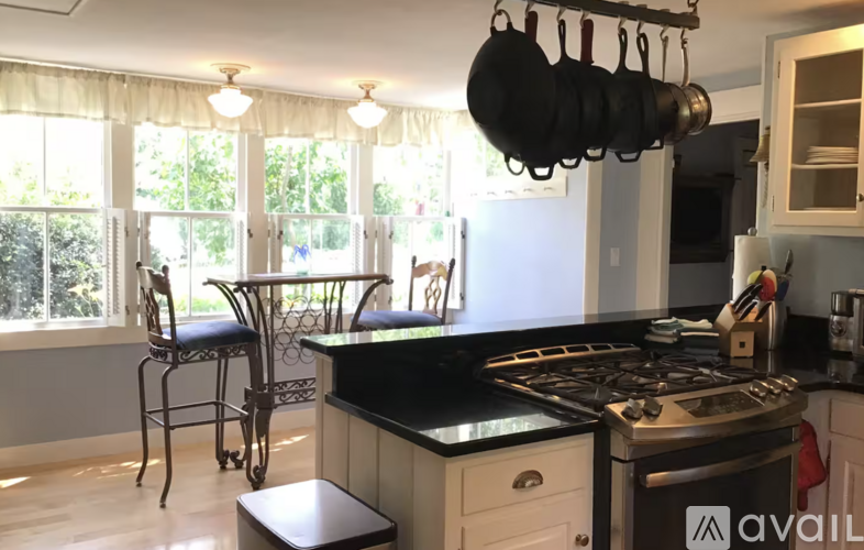 A kitchen with a black stove top and a hanging pot rack.