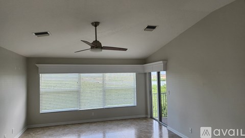 A room with a ceiling fan and sliding glass doors.