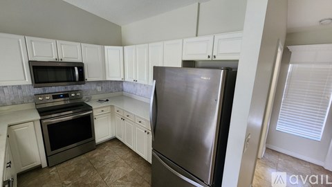 A kitchen with white cabinets and a stainless steel refrigerator.