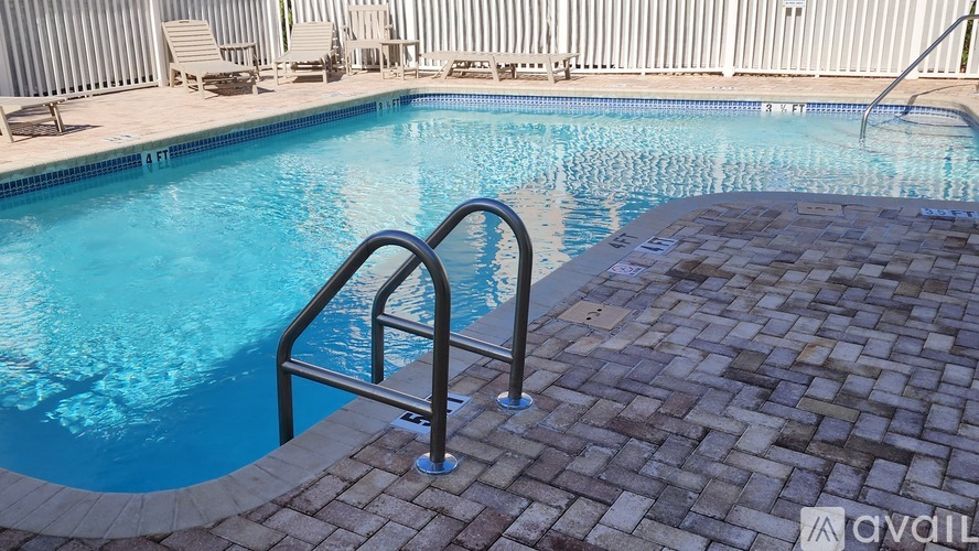 A pool with a metal ladder and a brick walkway.