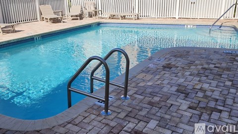 A pool with a metal ladder and a brick walkway.