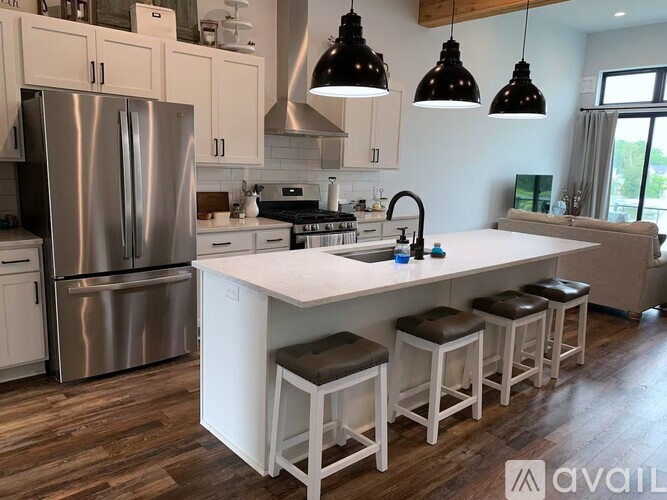 A kitchen with a white island and bar stools.