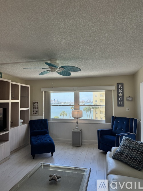 A living room with a blue chair and a fan.