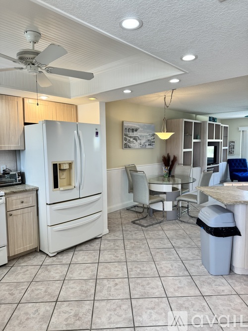 A kitchen with a white refrigerator and a dining table with chairs.