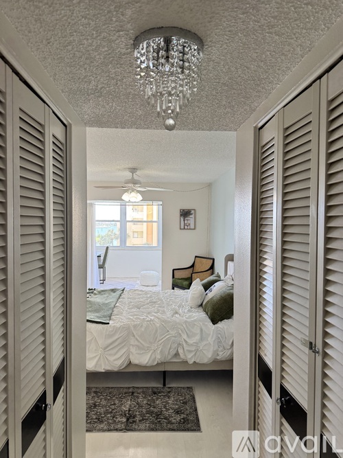 A bedroom with a bed, pillows, and a chandelier.