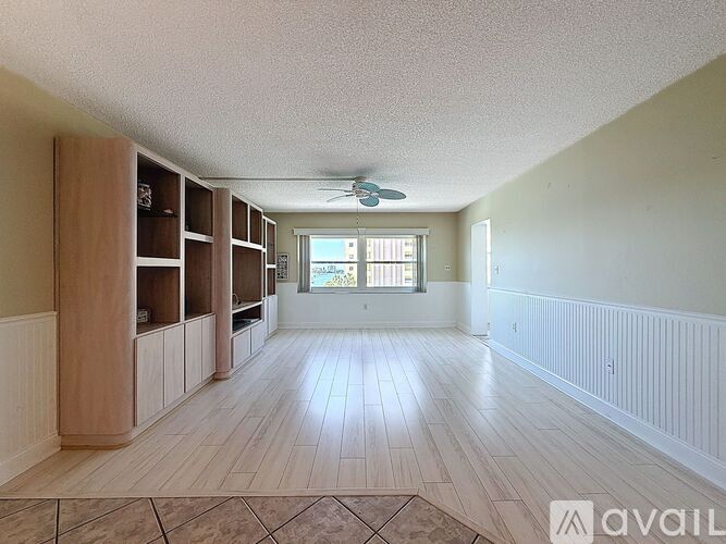 A spacious room with wooden floors and a ceiling fan.