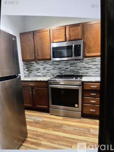 A kitchen with wooden cabinets and a stainless steel refrigerator.