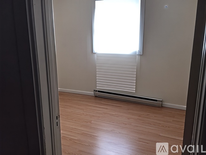 A room with wooden flooring and a window with blinds.