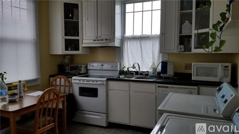 A kitchen with white appliances and a wooden chair.