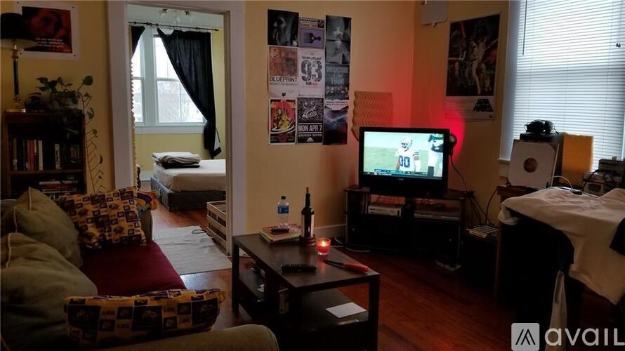 A living room with a couch, a coffee table, a television, and a bed.