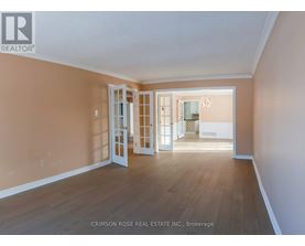 A room with a white door and a chandelier in the background.