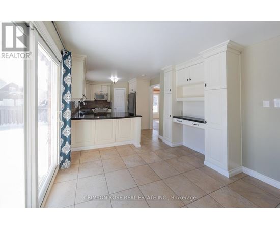 A spacious kitchen with white cabinets and a tiled floor.