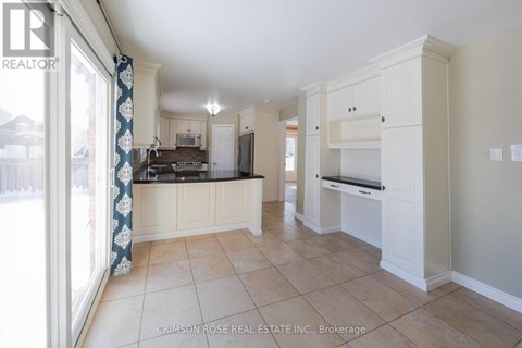 A spacious kitchen with white cabinets and a tiled floor.