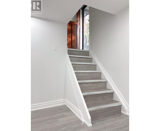 A staircase with a wooden handrail and grey steps.