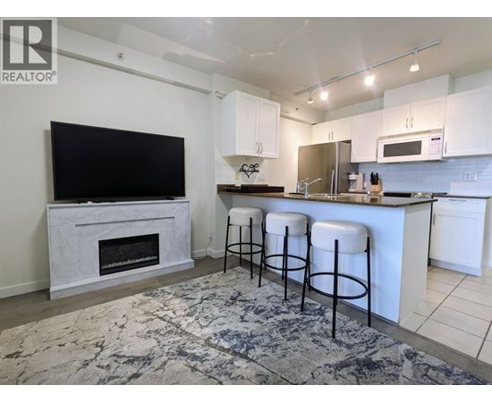 A kitchen with white cabinets and a black television.
