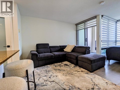 A living room with a grey sofa and a rug.