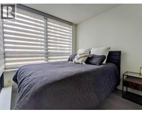 A bedroom with a bed, pillows, and a nightstand.