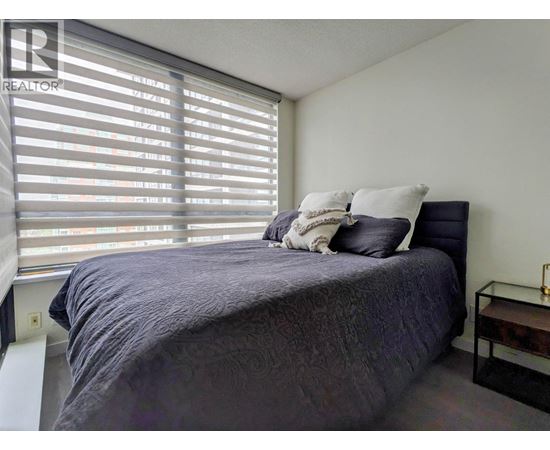 A bedroom with a bed, pillows, and a nightstand.