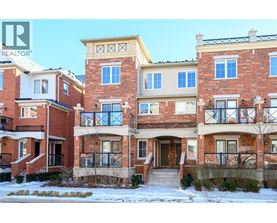 A row of red brick houses with a realtor logo in the corner.