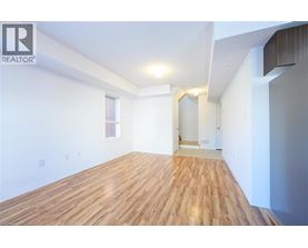 A spacious room with wooden flooring and white walls.