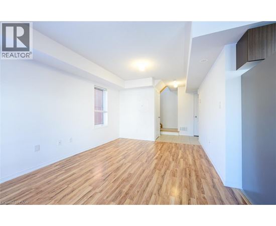A spacious room with wooden flooring and white walls.