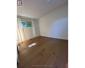 A room with wooden flooring and a window with white curtains.