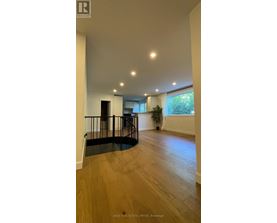 A spacious room with wooden flooring and a balcony with a railing.