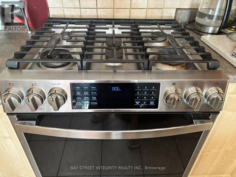 A stainless steel gas stove with a digital control panel.