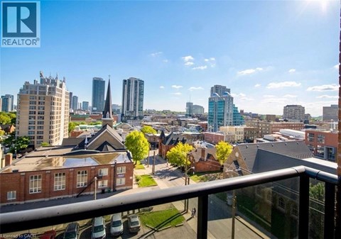 A cityscape with a mix of modern and older buildings, viewed from a balcony.