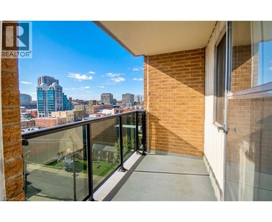 A balcony with a glass railing overlooking a cityscape.
